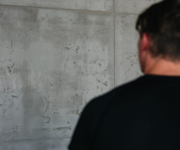 Malermeister vor einer fertiggestellten Betonoptik-Wand im Innenraum